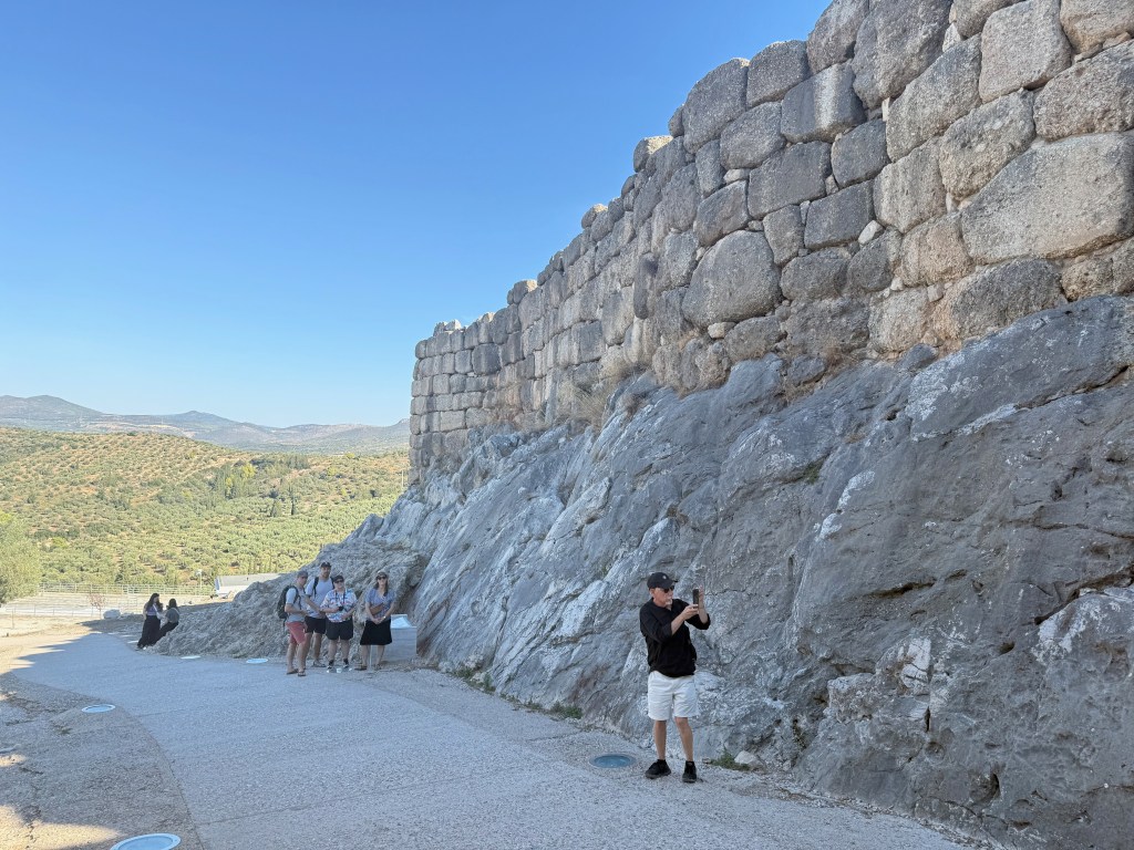 Visitors exploring ancient stone walls with scenic hills in the background.